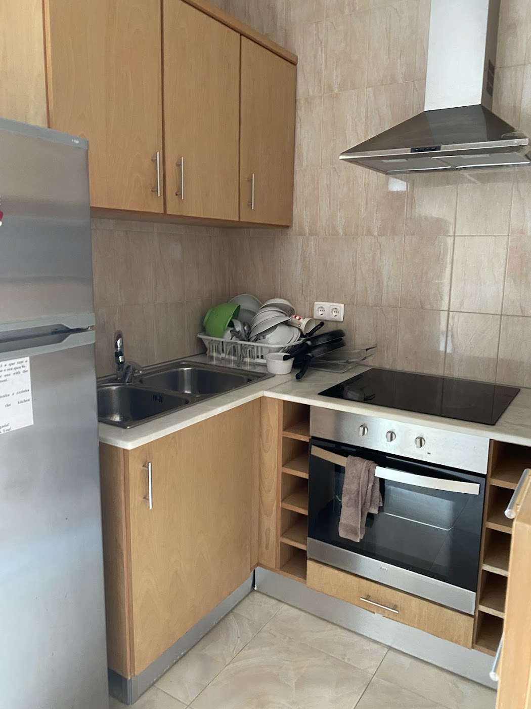 Compact kitchen with wooden cabinets, sink, cooktop, oven, and refrigerator